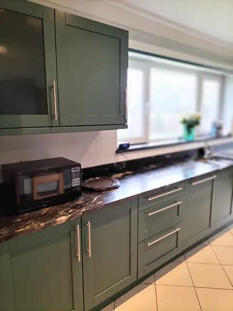Green shaker units with a dark granite worktop