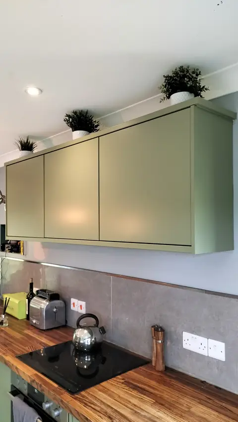 Sage green wall units above a wooden worktop