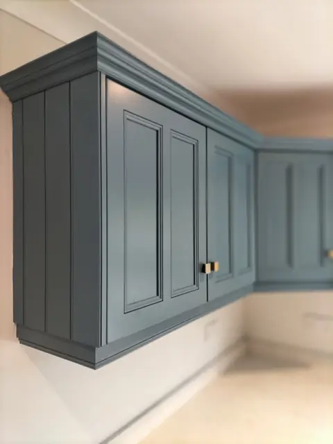 Dark teal corner wall cabinets with brass handles